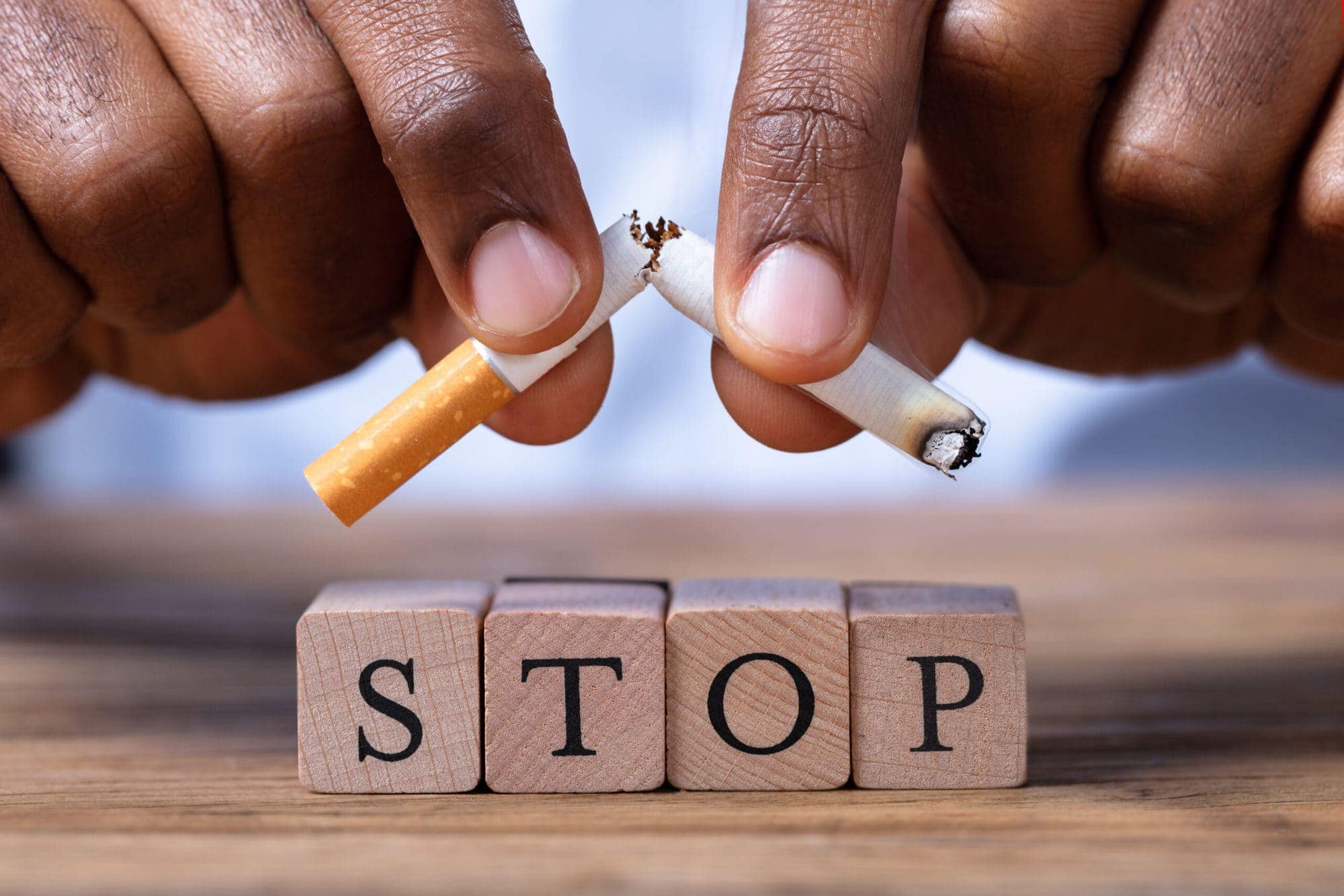 Close-up Of A Man's Hand Breaking Cigarette Over Wooden Stop Blocks